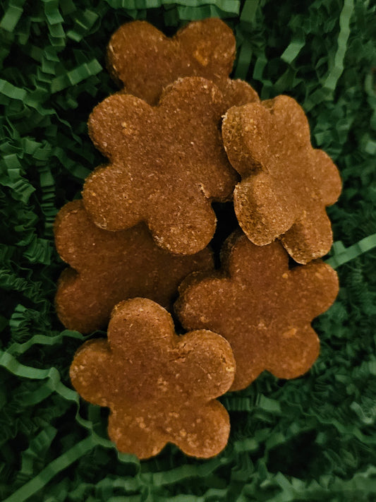Flower shaped horse treats with a green background made with oat flour molasses carrots.